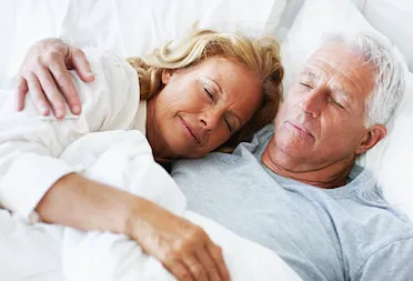 Older couple sleeping peacefully together in bed